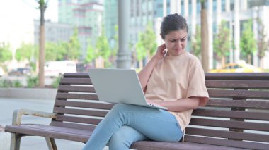 Laptop kullanırken boynu ağrıyan genç Hintli kadın.