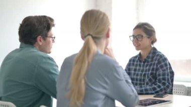 Ofisteki müşterilerle konuşan Hintli kadın.