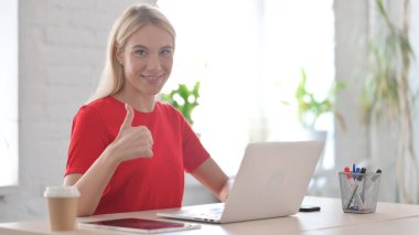 Young Woman showing Thumbs Up at Work