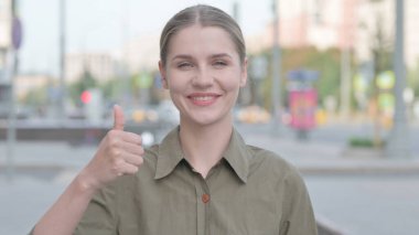 Thumbs Up By Excited Young Woman Outdoor