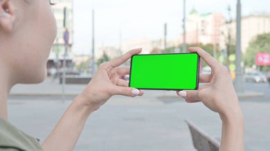 Close Up of Young Woman Holding Smartphone with Green Screen Outdoor