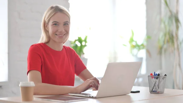 Fiatal Vigyorog Kamera Használata Közben Laptop Irodában — Stock Fotó