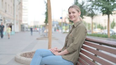 Young Woman Smiling at Camera while Sitting on Bench