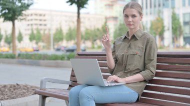 Rejecting Young Woman in Denial While using Laptop Sitting Outdoor on Bench