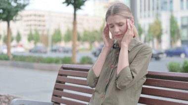 Distressed Young Woman with Headache Sitting Outdoor on Bench
