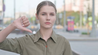 Thumbs Down By Young Woman Standing Outdoor