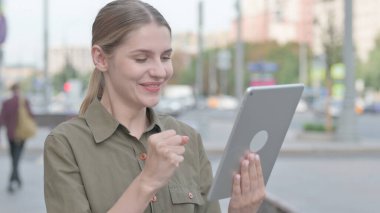 Young Woman Celebrating Success on Tablet Outdoor