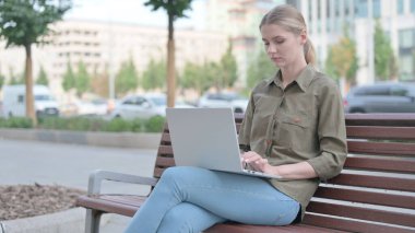 Busy Young Woman Using Laptop Sitting Outdoor on Bench