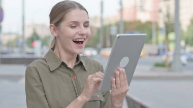 Young Woman Celebrating Success on Tablet Outdoor