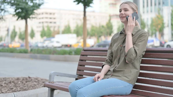 Молода Жінка Розмовляє Телефону Сидячи Відкритому Повітрі Лавці — стокове фото