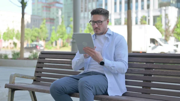 Mann Mittleren Alters Benutzt Tablet Während Draußen Auf Bank Sitzt — Stockfoto