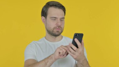 Sarı Arkaplan 'da Gelişigüzel Genç Adam Akıllı Telefon 