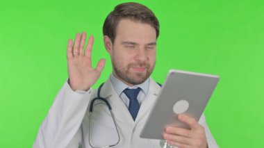 Video Call on Tablet by Young Adult Doctor on Green Background