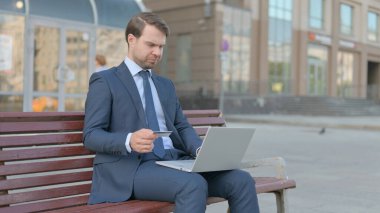 Young Businessman Reacting to Online Payment Problem while Sitting Outdoor