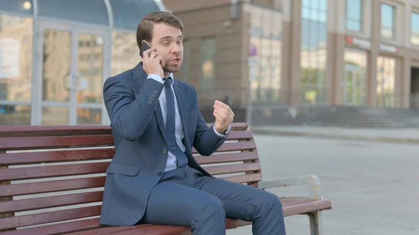 Angry Young Businessman Talking Phone While Sitting Outdoor Bench —  Fotos de Stock