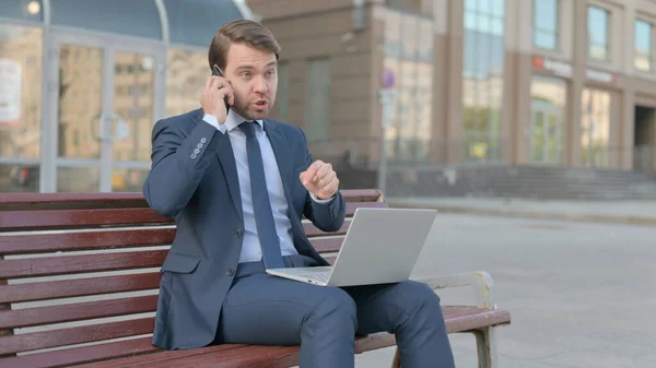 Wütender Junger Geschäftsmann Telefoniert Und Nutzt Laptop Während Draußen Auf — Stockfoto