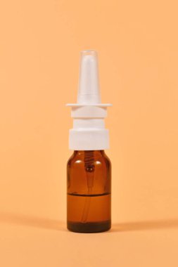 Sarı arka planda kahverengi cam burun spreyi şişesi