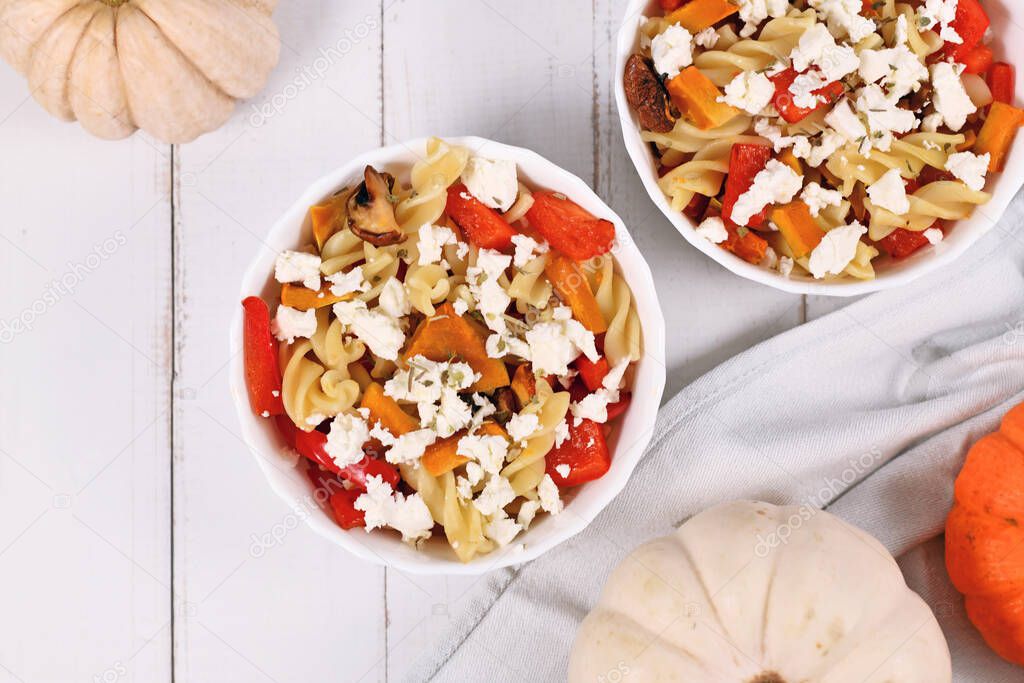 Bowl with Fusilli pasta, hokkaido pumpkin and bell pepper pieces topped with feta cheese