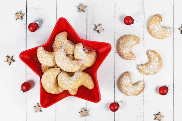 Top view of crescent Christmas cookies called 'Vanillekipferl', a traditional Austrian or German Christmas biscuits with nuts and icing sugar in bowl
