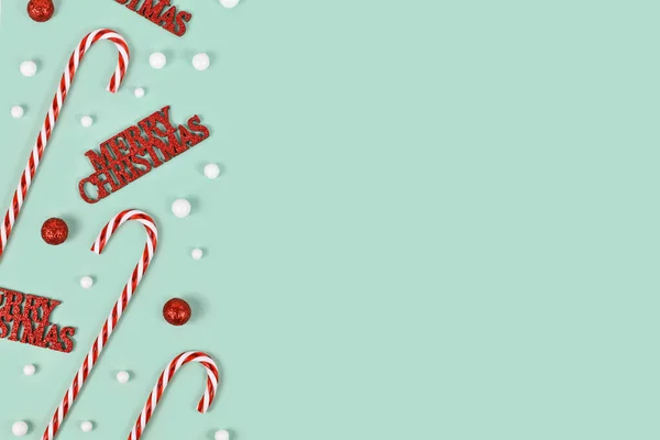 コピースペースとミントグリーンの背景に メリークリスマス テキスト キャンディーの杖と雪玉を持つクリスマスオーナメント — ストック写真