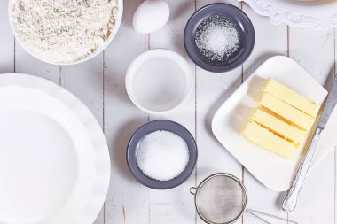 Kâselerdeki turta hamuru malzemeleri. Un, şeker, tuz, buzlu su, tereyağı ve yumurta ahşap masada. 