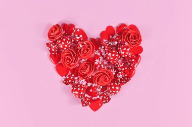 Sevgililer Günü 'nde kalp şekeri, kırmızı güller, kalpler ve pembe arka planda şeker parçacıkları şeklinde olur.