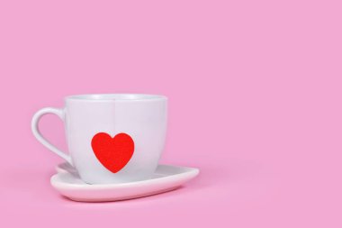 Kırmızı kalp şeklinde çay fincanı. Pembe arka planda, fotokopi alanı ile birlikte.
