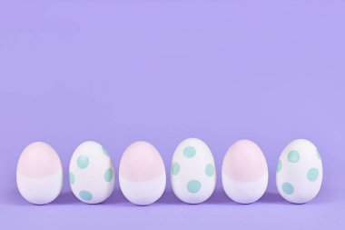 Pastel boyalı nane yeşili ve pembe paskalya yumurtaları menekşe arka planda 