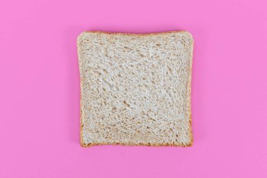 Pembe arka planda dilimlenmiş buğday ekmeği.