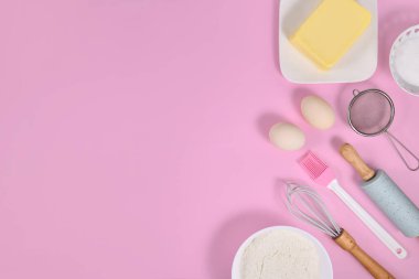 Pembe zemin üzerinde kek hamuru malzemeleri ve pişirme araçları kopyalama alanı ile