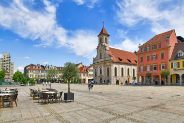 Ludwigsburg, Germany - July 2022: Market square with outdoor restaurant tables and church 'Zur Heiligsten Dreieinigkeit'