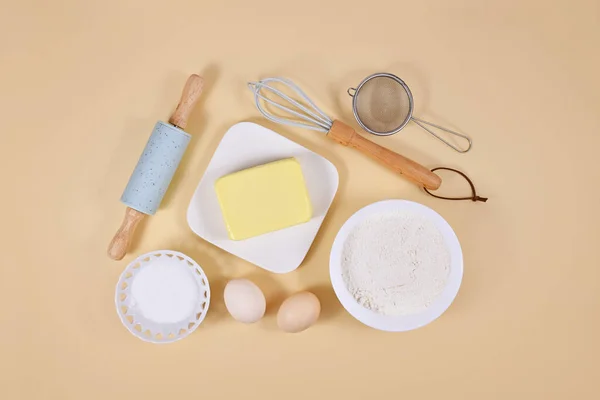 Cake dough ingredients and baking tools on beige background
