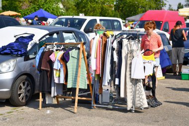 Heidelberg, Germany - August 2022: Women looking through rack with old second hand clothes at flea market