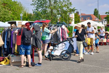 Heidelberg, Germany - August 2022: People looking through rack with old second hand clothes at flea market