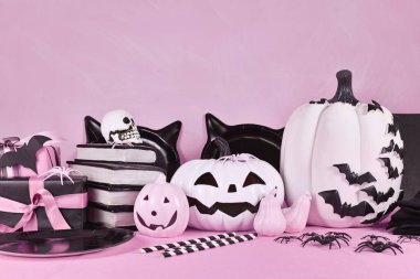 Pink Halloween decor with black and white pumpkins, spell books and spiders with copy space