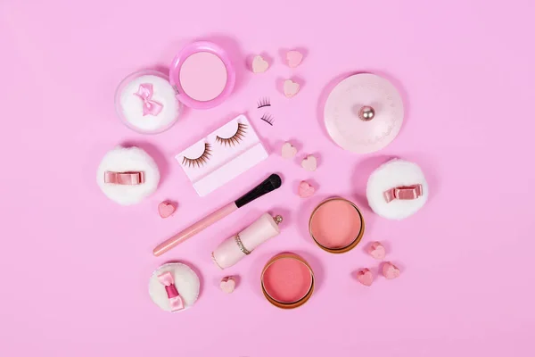 Cute pink makeup beauty products like brushes, powder or lipstick on pink background