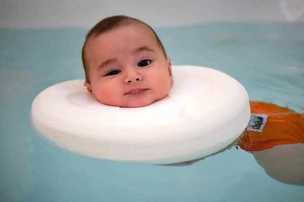 Bebek jakuzide eğleniyor. Bebekler için spa. Çocuklar için hidroterapi seansı. Bebek yüzme