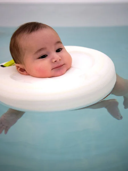 Bebek jakuzide eğleniyor. Bebekler için spa. Çocuklar için hidroterapi seansı. Bebek yüzme