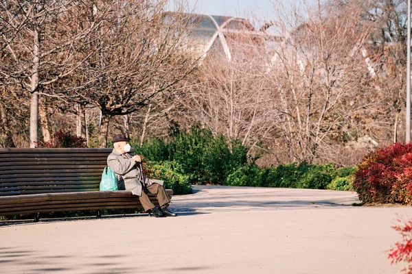 Madrid, Spain - 13 january 2022. Senior man enjoying the sun sitting on park bench in Madrid Rio. Retirement concept