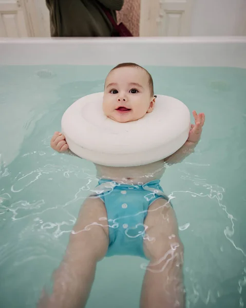Bebek jakuzide eğleniyor. Bebekler için spa. Çocuklar için hidroterapi seansı. Bebek yüzme