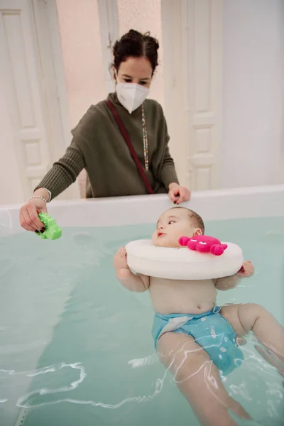 Bebek jakuzide eğleniyor. Bebekler için spa. Çocuklar için hidroterapi seansı. Bebek yüzme