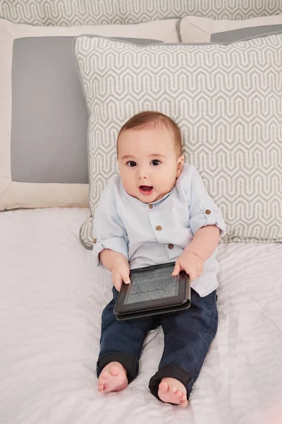 Ребенок с помощью смартфона, сидящий на кровати — стоковое фото
