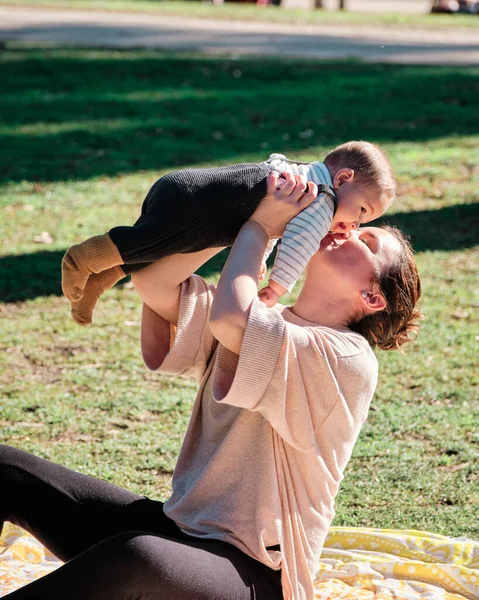 Ung kvinna leker med sitt barn i en allmän park på en solig dag — Stockfoto