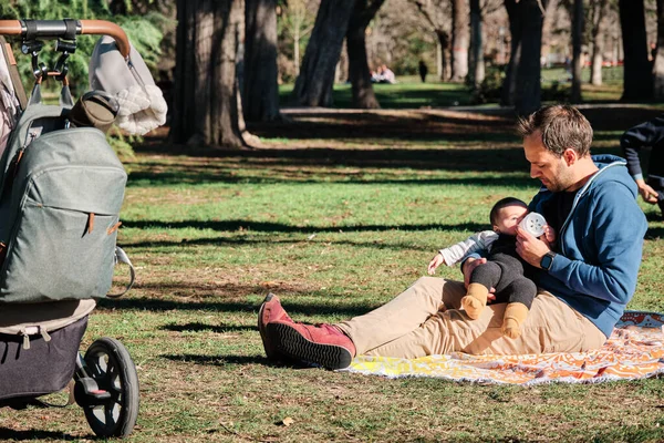 Joven biberón alimentando a su hijo al aire libre en un parque público — Foto de Stock