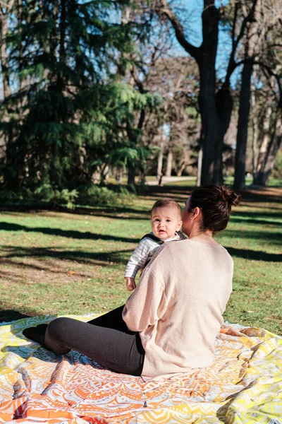 Ung kvinna leker med sitt barn i en allmän park på en solig dag — Stockfoto