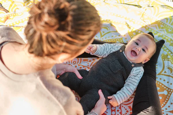 Ung kvinna leker med sitt barn i en allmän park på en solig dag — Stockfoto