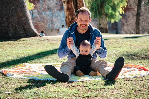 Ung man leker med sitt barn i en allmän park på en solig dag — Stockfoto