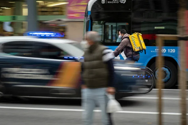 Madrid, İspanya - 28 Kasım 2020. Glovo teslimat şoförü teslimat yapıyor. Motosikletli şehir merkezinde yoğun bir caddede gidiyor.
