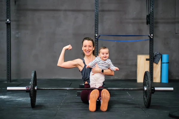 Молодая женщина фитнес и ребенок в тренажерном зале Стоковое Изображение