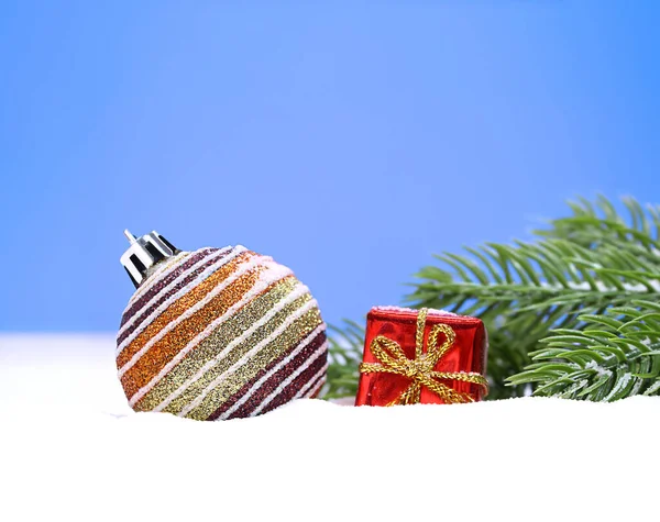Weihnachtlich Gestreifte Glänzende Kugel Mit Kleiner Roter Geschenkschachtel Auf Schnee Stockbild